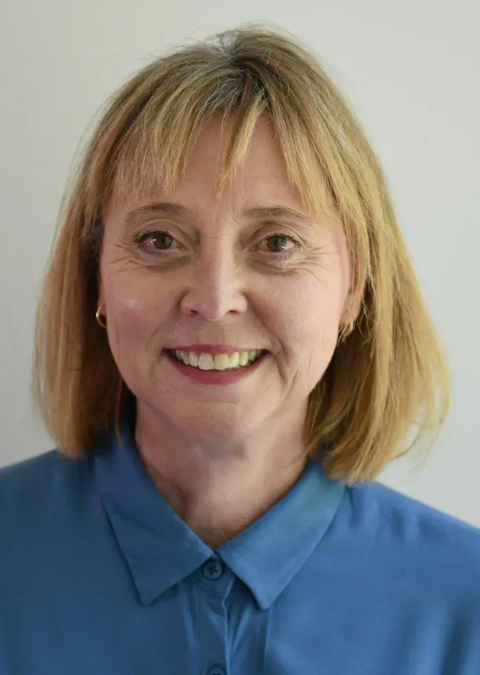 Portrait photo d'une femme souriante avec une coiffure blonde et un chemisier bleu